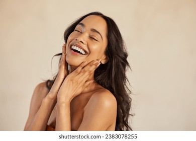 Mujer joven multiétnica tocando su rostro limpio y saludable contra su fondo con los ojos cerrados. Mujer hispana latina sintiéndose bien. Retrato de belleza natural de una chica mexicana de pelo largo negro. Foto de stock