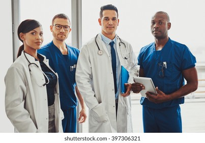 Multiracial team av läkare på ett sjukhus som står i en korridor redo att göra en avdelning runt Stockfoto