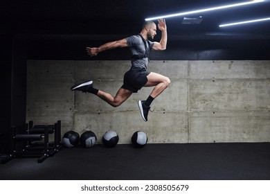 A muscular man captured in air as he jumps in a modern gym, showcasing his athleticism, power, and determination through a highintensity fitness routine Foto stock
