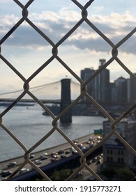 New York City, NY, USA -November 07, 2015: Blurred View of NYC, Brooklyn Bridge and the East River through a fence. FDR Drive on the border. Foto de contenido editorial de stock
