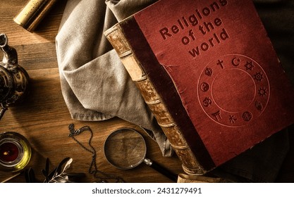 Old and deteriorated book of the religions of the world with engraved letters on the cover and ancient objects of study and adventure on wooden table. Top view.: stockfoto
