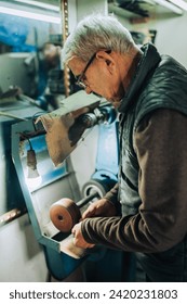 古い靴職人は、彼のワークショップでシャープ化ツールを使用しています。靴屋が仕事場で靴を作っている。の写真素材