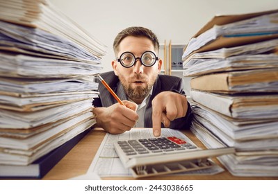 過労のビジネスマン スーツと面白いメガネは、フォルダの山と紙のスタックとオフィスで彼の職場で机で働いています。データを分析して計算を行う疲れた会計士。の写真素材