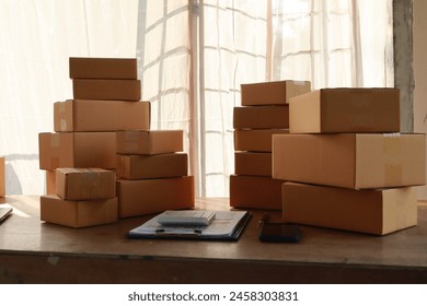 packages await delivery in a small business warehouse. The entrepreneur manages orders online, using a computer for logistics and marketing. Boxes packed for shipment, the bustling e-commerce economy 库存照片