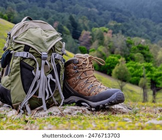 Une paire de bottes de randonnée usées, recouverte de poussière et de poussière sur un terrain montagneux, et un sac à dos de voyage. Concept, voyage d'aventure.
 : photo de stock