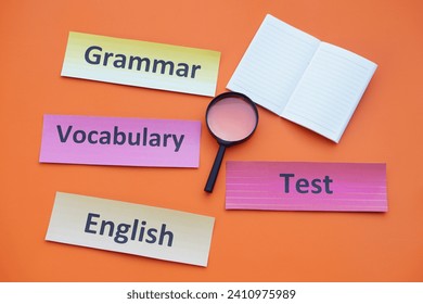 テキスト付きの紙のワードカード語彙、英語、文法、テスト。虫眼鏡。オレンジの背景。コンセプト。教材。言語を学ぶ。                                        の写真素材