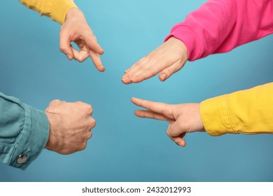 People playing rock, paper and scissors on light blue background, closeup Stock-foto