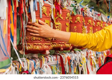 Person pilgrim female hand touching turning spinning Buddhist prayer wheel at Buddhist monastery. Prayer wheels in Buddhist stupa temple. Buddhism religion concept Foto stock