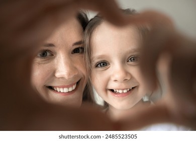 若い母親と小さなかわいい娘のポートレート結合された指で心のシンボルを示すカメラを見て笑って、接写。無条件の愛、幸せな母性、養子縁組、育児の写真素材