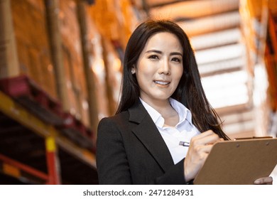 Portrait of Asian business woman or vice president smiling and holding clipboard at warehouse factory. Confidence people with positive vision working at import export company concept with copy space Adlı Stok Fotoğraf
