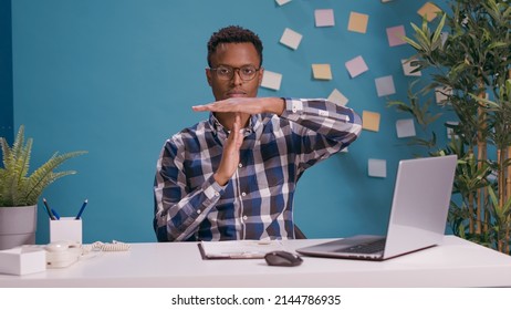 Portrait of employee showing timeout gesture and looking at camera, expressing wish to take break and pause from work. Overworked man asking for half time, to control limits finish. Arkistovalokuva