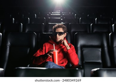 Portrait of a handsome man who drinks soda at the cinema. A lonely man at the premiere of a movie. 3D glasses ภาพถ่ายสต็อก