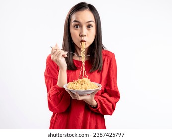 A portrait of a happy Asian woman wearing a red shirt, eating noodles. Isolated against a white background. Stock-foto