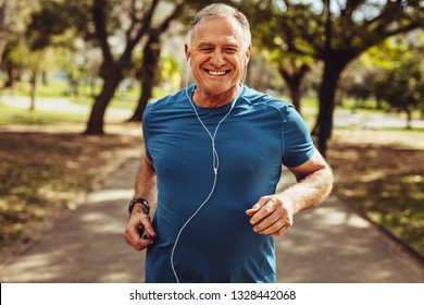 공원에서 뛰는 운동복 입은 노인 초상화.이어폰을 이용해 음악을 들으며 뛰어다니는 웃고 있는 남자의 입을 닫으세요. 스톡 사진