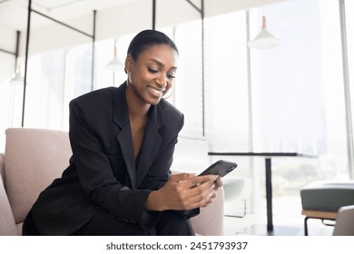 Positive beautiful Black business professional lady using application on cellphone for job communication, typing message on work chat, smiling, holding smartphone Stock fotografie