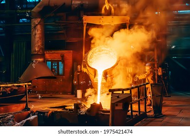 Pouring molten metal into mold from ladle container in foundry metallurgical factory workshop, iron cast, heavy industrial background Foto stock