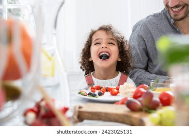 Playful boy with his father eating blueberries at table Stock-foto