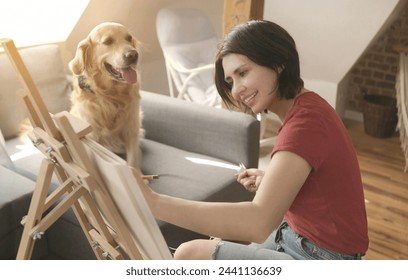 Pretty girl artist drawing sketch with golden retriever dog using pencil and canvas. Beautiful young woman painting portrait of cute doggy pet स्टॉक फ़ोटो