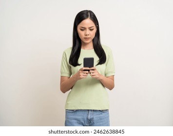 Bastante joven asiática que utiliza el teléfono inteligente se siente molesto confundido mal deprimido emocional de pie sobre fondo blanco aislado. Sujetando el celular. Pensamiento y estrés Foto de stock