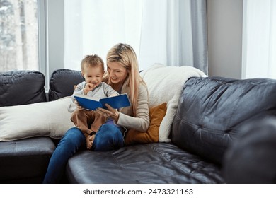 Reading, mama and boy in living room with book, teaching and learning in family home and education. Knowledge, fantasy and storytelling, mother and son relax on sofa together with love, care and calm Foto stock
