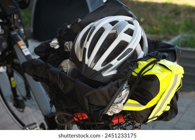 自転車のヘルメット、反射ベスト、自転車ロック、雨のカバー、および防水シートが含まれている自転車のラゲッジラックを強調するEバイクの背面。背景には自転車のテントが見えます。の写真素材