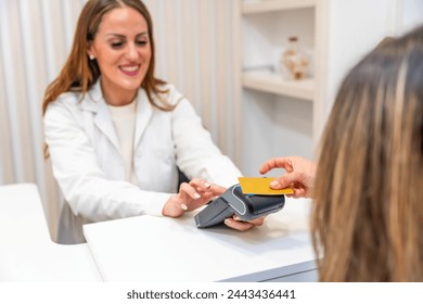 Rear view of a female client paying using credit card in the reception of a beautician clinic Stockfotó