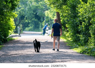 Vista trasera de un hombre caminando sobre su perro en el camino principal alrededor del estanque del sur en Babylon Village New York. Foto de stock