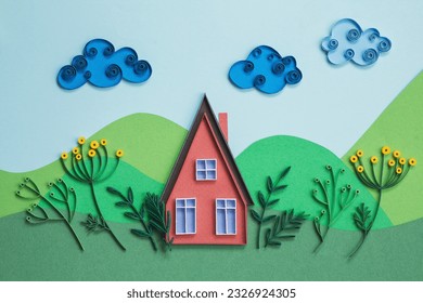 Red paper house with blue windows and garden isolated on a green and blue paper background. Small house made in quilling technique. Hand made of paper. Home sweet home in a summer happy day. Stock-foto