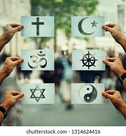 Religion conflicts as global issue concept. Human hands holding different paper with faith symbols over crowded street scene. Relations between different people doctrines and beliefs, social problem. Stock Photo
