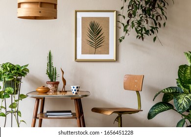Retro interior design of living room with stylish vintage chair and table, plants, cacti, personal accessories and gold mock up poster frame on the beige wall. Elegant home decor. Template.  Stock Photo