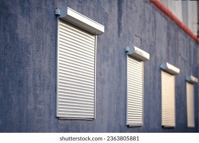 Rolling shutters, windows with closed roller shutters. House facade with window on first floor, security and protection concept. Selective focus Foto stock