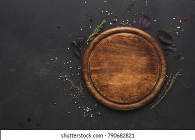 Round wooden plate with herbs and salt on dark wooden background top view Stock Photo