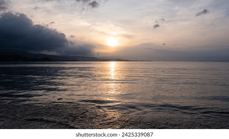 Scenic view overlooking calm placid ocean during sunset with sunlight reflecting over surface of water on the tropical island of Timor-Leste in Southeast Asia Foto stock