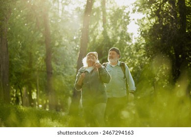 Senior couple, man and woman taking peaceful walk in park, enjoying tranquility and the beauty of nature. Sunlight and greenery. Concept of sport, aging, active and healthy lifestyle, health care – Ảnh có sẵn
