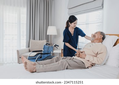 Senior Asian man laying on bed receives medical help for injury by Asian nurse, doctor woman assisting स्टॉक फ़ोटो