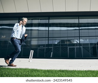 senior businessman in a rush  running and using a phone smartphone outdoors Foto stock