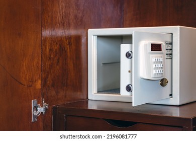Security open metal safe with empty space inside in a wooden shelf. White safe box open door. Safe box with electronic lock in the hotel or home. Selective Focus on locking mechanism of small safes. – Ảnh có sẵn