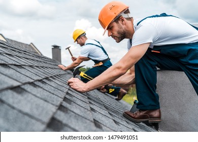 ハンサムなハンディマンが同僚と屋根を修理する際の限定フォーカス の写真素材
