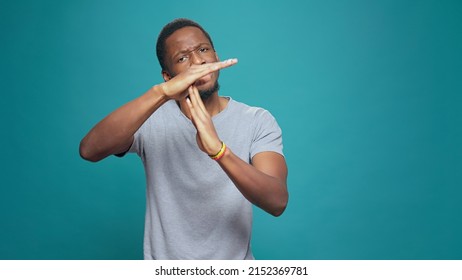 Serious tired person advertising timeout symbol with hands, doing t shape sign to express half time and break. Exhausted man refusing to work, declining and ingoring control. Stop gesture. Arkistovalokuva