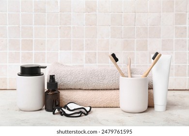 Set of bath supplies with toothbrushes on table against light tile wall: stockfoto