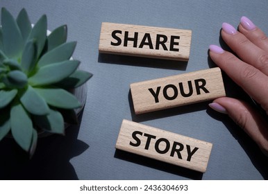 Share your story symbol. Wooden blocks with words Share your story. Beautiful grey background. Businessman hand. Business and Share your story concept. Copy space. 库存照片