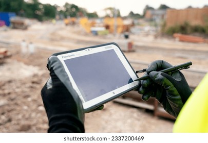 Sheffield (Royaume-Uni) - Juillet 08 2023 Inspecteur ingénieur de site utilisant un ordinateur de contrôleur de tablette robuste pour exploiter la station totale EDM pour l'installation et l'arpentage en gros plan : photo de stock éditoriale