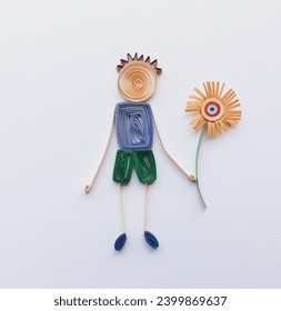 Simple colorful stick figure boy giving flower, love, Mother's Day, boy with blue shirt make in quilling art isolated on white background. Hand made of paper quilling technique. handicraft at home. Stock-foto