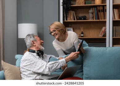 Стоковая фотография: Simple living. Elderly retired couple enjoying their retirement, reminiscing entertaining in their warm home. Senior people evoking memories, happy people in cozy home, love and respect for each other