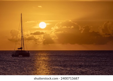 Une seule silhouette de catamaran contre un soleil couchant : photo de stock