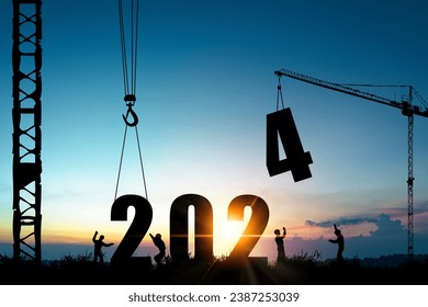 歓迎2024年新年パーティーの準備と新しいビジネスを変更するためのクレーンと曇りの青空と建設労働者のシルエット。の写真素材
