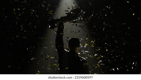 Silhouette of race car driver celebrating the win in a race against bright stadium lights, rising a trophy over his head – Ảnh có sẵn