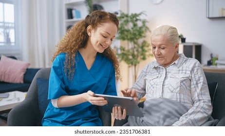 A social service worker assists a senior woman in using a tablet to find information online 库存照片