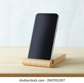 smartphone in wood stand on light wooden table Stockfoto