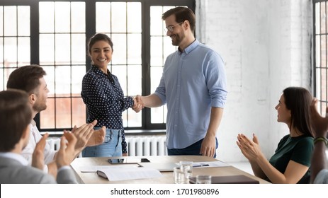 Smiling businessman shake hand of overjoyed Indian female newcomer at office meeting, diverse colleagues applaud to male employer handshake excited biracial woman worker, greeting with job promotion Arkistovalokuva